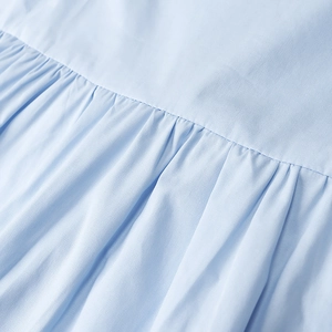 Makro-Detail der hellblauen plissierten Stofftextur und feinen Nähten am Kleid