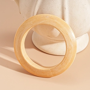 Close-up of a thick vintage wooden texture open bangle leaning on a ceramic pot