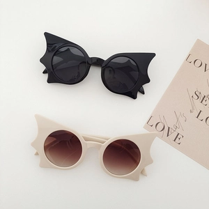 Flat lay of creative bat-shaped sunglasses in black and cream white colors