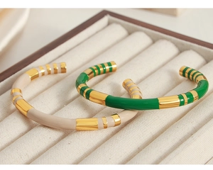 Macro detail of enamel-glazed gold-plated open bangles in green and beige colors