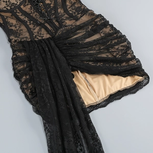 Dettaglio dell'abito in pizzo nero con ricami floreali, fodera beige e lacci decorativi in vita