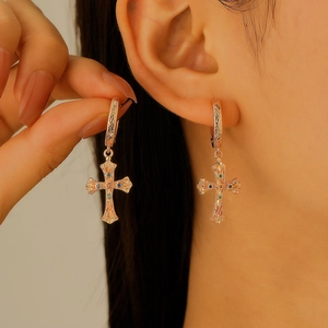 Golden cross hoop earrings with intricate textured engravings and colorful gemstones