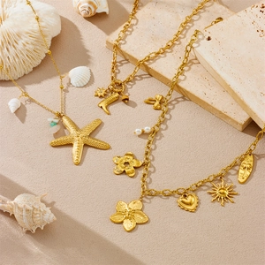 Detail of beach-inspired gold necklaces with starfish, seahorse, and sun pendants