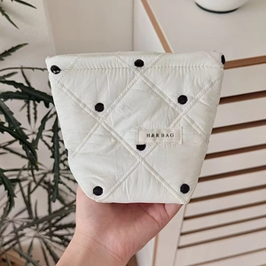 Gros plan détaillé de la trousse de maquillage matelassée blanche à pois avec logo H&R BAG