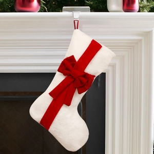 Plush Christmas stocking with large red bow decoration hanging on festive fireplace mantel
