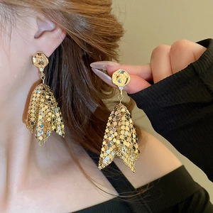Close-up of elegant gold tassel earrings with textured sequins on model's ear