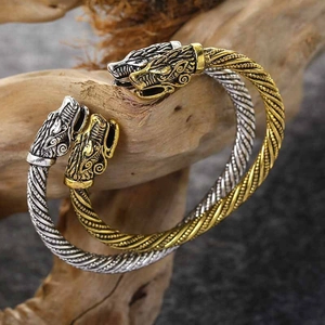 Detailed view of Viking dragon head bracelets in gold and silver on natural driftwood