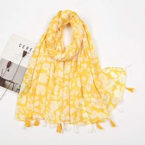 Detail of a bright yellow scarf with white daisy print and elegant fringed tassels