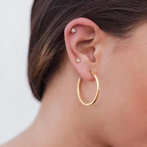 Golden hoop earrings with zircon flower ear studs shown on model for layered styling