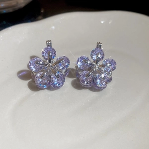 Macro view of floral stud earrings featuring purple zircon crystals and silver metal claws