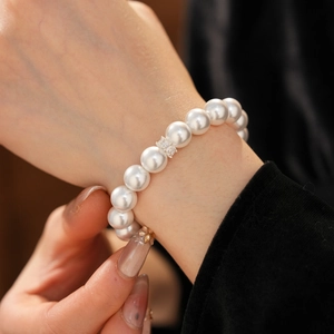 Détail d'un élégant bracelet en perles avec un charme en zircon rectangle sur un poignet