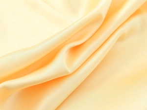 Gros plan du tissu en satin champagne montrant la texture soyeuse et le drapé