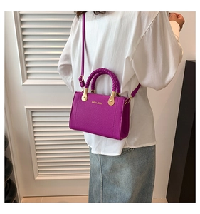Détail du sac bandoulière violet avec poignée tressée et finitions dorées sur modèle