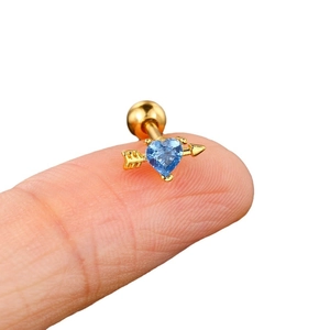 Gold heart and arrow cartilage stud with a vibrant blue crystal stone on finger