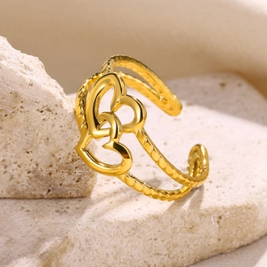Macro shot of gold double heart open ring with wavy texture on a natural stone base