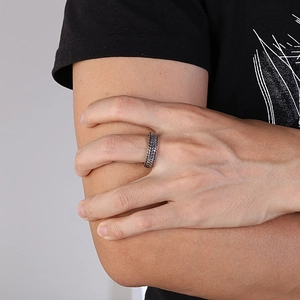 Detailed close-up of a silver textured steel ring with leaf pattern on a model finger