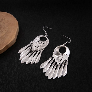 Detailed macro shot of silver tribal leaf tassel earrings with intricate hollow carvings