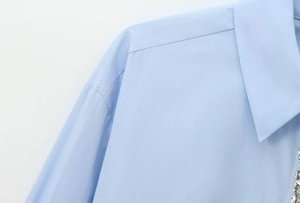 Close-up of light blue poplin shirt collar featuring sparkling white rhinestone embellishments