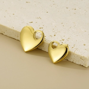 Golden stainless steel heart pendants in two sizes displayed on stone steps