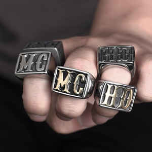 Macro detail of men's silver and gold stainless steel signet rings with embossed letters