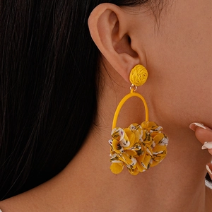 Detail of yellow fabric floral drop earrings featuring woven texture and floral petals