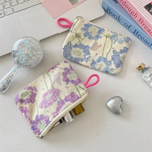 Floral cotton makeup pouch with pink braided rope zipper detail on white desktop
