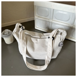 Detail of off-white corduroy crossbody bag with adjustable strap and sheep charm