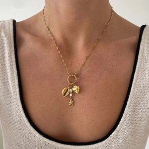 Detailed close-up of gold paperclip chain necklace with pearl and seashell pendants
