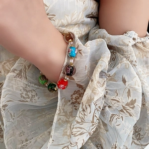 Close-up of a women's bracelet with colorful floral glass beads and golden spacers