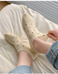 Close-up of beige polka dot no-show sock showing elastic cuff on hand-worn detail