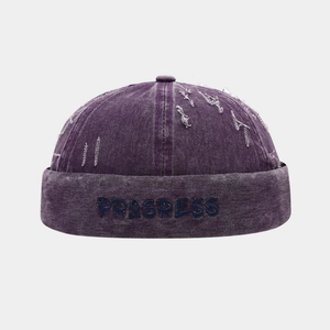 Dettaglio del cappello miki in denim viola con ricamo PROGRESS blu scuro sul bordo