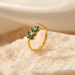 Adjustable leaf-shaped stainless steel ring with green crystals on stone background