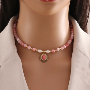 Handmade necklace with pink beads, white pearls, and a gold filigree red stone pendant