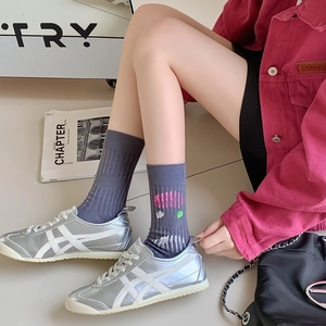 Gray cotton crew socks with pink and green abstract patterns styled with sneakers