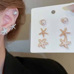 Detail view of starfish and pearl earring set with rose gold accents and enamel finish