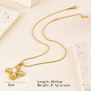 French retro gold necklace with pearl clover pendant on a textured stone display
