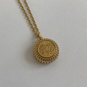Detailed close-up of gold Aries zodiac pendant with ram head icon and grooved edge detail