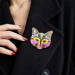 Vintage feline mask brooch with colorful enamel and sparkling rhinestones on a coat