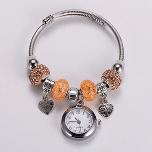 Detail of silver cable bracelet with heart pendant, quartz watch charm, and champagne beads