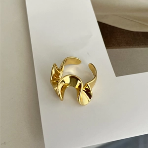 Dettaglio ravvicinato dell'anello in ottone dorato con design a onde e finitura lucida
