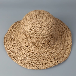 Detailed weave of a wide-brimmed paper straw hat with natural tan spiral texture