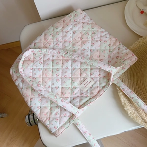 Detail of floral quilted cotton tote bag with a woven label and delicate shoulder straps
