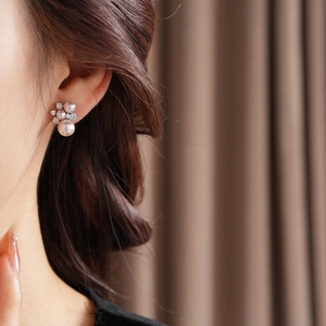 Close-up of flower pearl earrings with zircon inlay worn by a model in elegant lighting