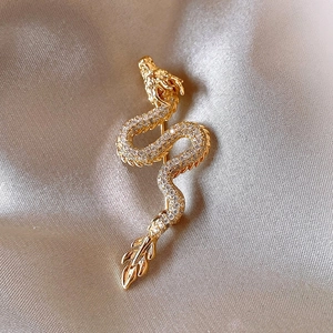 Gold plated dragon brooch with sparkling zircons on elegant champagne satin backdrop