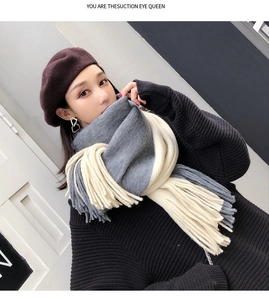 Detail of gray and beige color-block knitted scarf with fringe, worn by a model