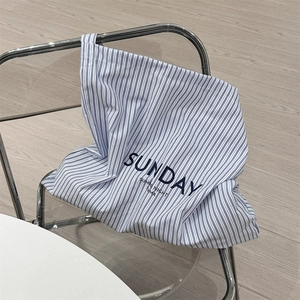 Detail of blue and white striped canvas bag with SUNDAY lettering on a chair