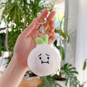 Close-up of cute plush garlic keychain with embroidered face and green leaves