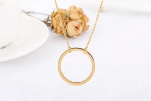 Detail of elegant gold hollow geometric circular necklace set against white decor