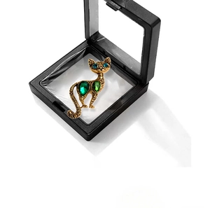 Close-up of vintage gold cat brooch with green crystals and blue eyes in a display box