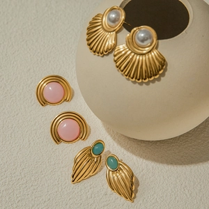 Close-up of vintage gold studs with white pearl and green teardrop gemstone details